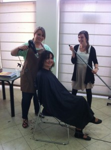 Laura cutting Leah's hair; Mary Brett on hair sweeping duty